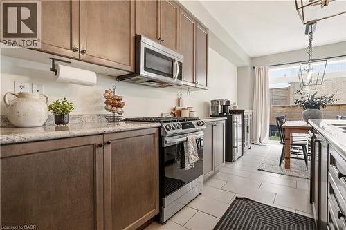 Kitchen with stainless steel appliances, wine cooler, decorative light fixtures, and light stone countertops - 105 Larry Crescent, Caledonia, ON - Indoor Photo Showing Kitchen With Stainless Steel Kitchen With Upgraded Kitchen