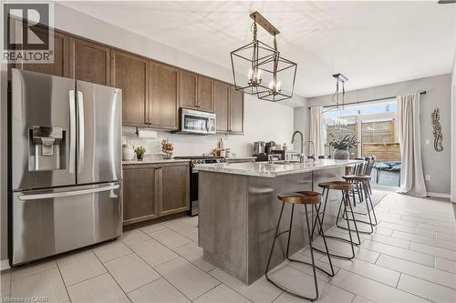 Kitchen with stainless steel appliances, an island with sink, a breakfast bar, suspended lighting, and light stone counters - 105 Larry Crescent, Caledonia, ON - Indoor Photo Showing Kitchen With Stainless Steel Kitchen With Upgraded Kitchen