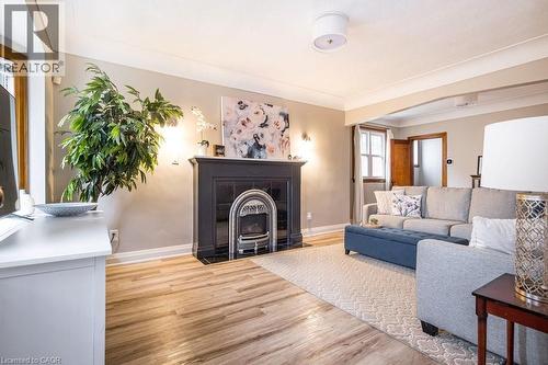 Living area featuring light wood-type flooring, a fireplace with flush hearth, and arched walkways - 143 Huxley Avenue S, Hamilton, ON - Indoor Photo Showing Living Room With Fireplace