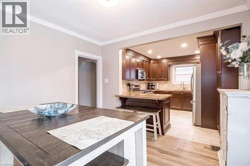 Kitchen featuring a peninsula, stainless steel appliances, tasteful backsplash, light stone counters, and crown molding - 143 Huxley Avenue S, Hamilton, ON - Indoor Photo Showing Kitchen