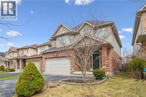 View of front of property with asphalt driveway, brick siding, a garage, and a front lawn - 512 Wood Nettle Way, Waterloo, ON - Outdoor With Facade