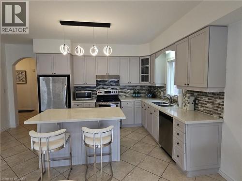 Modern kitchen featuring light cabinetry, quartz countertops, a stone mosaic tile backsplash, stainless steel appliances, and an island with pendant lighting - 512 Wood Nettle Way, Waterloo, ON - Indoor Photo Showing Kitchen With Double Sink