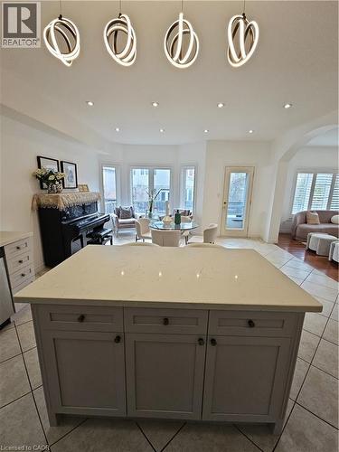 Kitchen island featuring a light-toned countertop, integrated cabinetry, and contemporary pendant lighting - 512 Wood Nettle Way, Waterloo, ON - Indoor