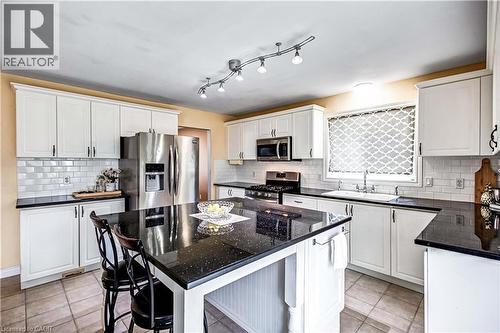 Kitchen with stainless steel appliances, dark stone counters, a kitchen breakfast bar, white cabinets, and a center island - 65 Thistlemoor Drive, Caledonia, ON - Indoor Photo Showing Kitchen With Upgraded Kitchen