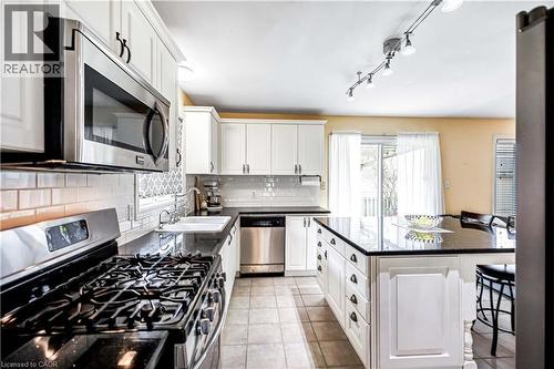 Kitchen with stainless steel appliances, a breakfast bar, white cabinets, and a center island - 65 Thistlemoor Drive, Caledonia, ON - Indoor Photo Showing Kitchen With Upgraded Kitchen