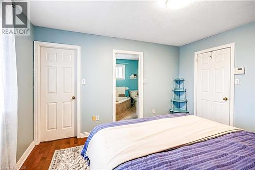 Bedroom with dark wood-style flooring, connected bathroom, and a textured ceiling - 65 Thistlemoor Drive, Caledonia, ON - Indoor Photo Showing Bedroom