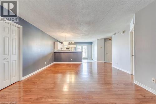 Unfurnished living room featuring a chandelier, light wood-style flooring, and a textured ceiling - 1411 Walker'S Line Unit# 302, Burlington, ON - Indoor