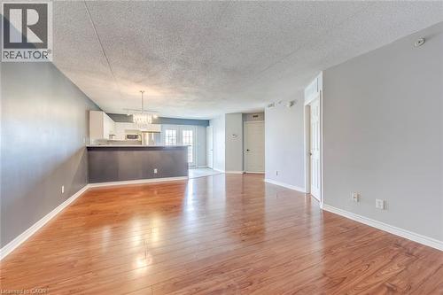 Unfurnished living room featuring a textured ceiling, light wood-type flooring, and hanging lights - 1411 Walker'S Line Unit# 302, Burlington, ON - Indoor