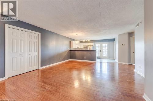 Unfurnished living room with french doors, a textured ceiling, light wood-type flooring, and suspended lighting - 1411 Walker'S Line Unit# 302, Burlington, ON - Indoor Photo Showing Other Room