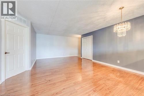 Spare room featuring suspended lighting, a textured ceiling, and light wood-style floors - 1411 Walker'S Line Unit# 302, Burlington, ON - Indoor Photo Showing Other Room