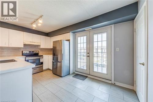 Kitchen featuring stainless steel appliances, white cabinets, french doors, backsplash, and a textured ceiling - 1411 Walker'S Line Unit# 302, Burlington, ON - Indoor Photo Showing Kitchen With Double Sink