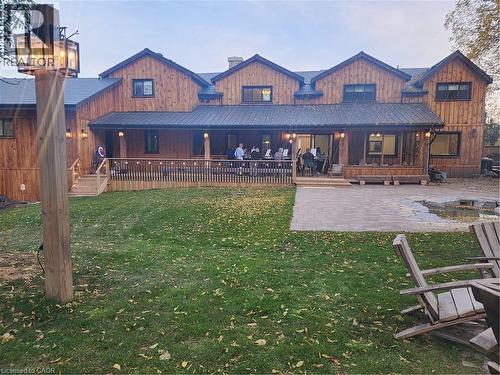 Back of house with a lawn, an outdoor fire pit, a metal roof, board and batten siding, and a patio area - 2019 Dundas Street, Burlington, ON - Outdoor With Deck Patio Veranda