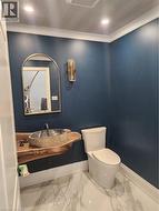 Bathroom with recessed lighting, vanity, ornamental molding, and light marble finish flooring - 