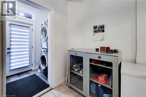 Laundry room with stacked washing machine and dryer and light tile patterned flooring - 97 Keith Street, Hamilton, ON - Indoor Photo Showing Laundry Room