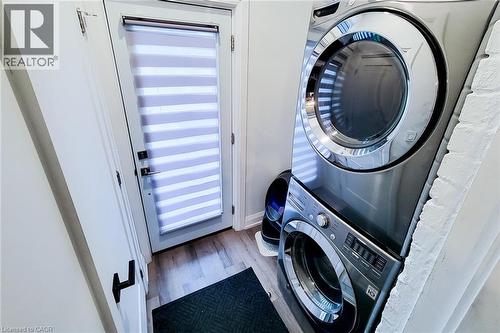 Laundry area with wood finished floors and stacked washing machine and dryer - 97 Keith Street, Hamilton, ON - Indoor Photo Showing Laundry Room