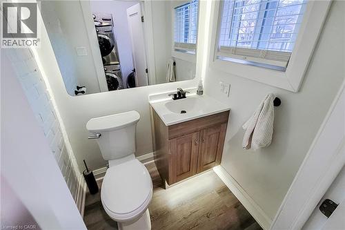Half bathroom featuring vanity, light wood-style flooring, and stacked washer and dryer - 97 Keith Street, Hamilton, ON - Indoor Photo Showing Bathroom