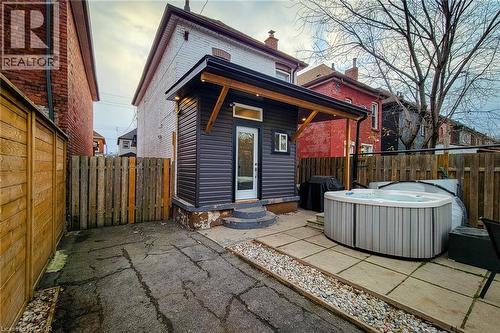 Rear view of property featuring a patio area, entry steps, a fenced backyard, a hot tub, and a chimney - 97 Keith Street, Hamilton, ON - Outdoor