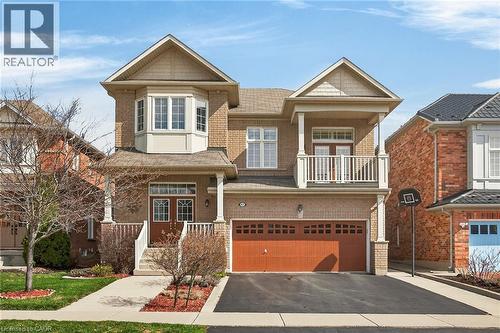 Craftsman-style house with asphalt driveway, a garage, covered porch, and brick siding - 97 Sirente Drive, Hamilton, ON - Outdoor With Balcony With Facade