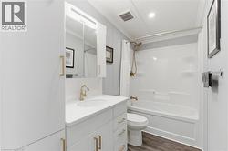 Full bathroom with vanity, dark wood-style floors, shower / bath combo with shower curtain, and crown molding - 