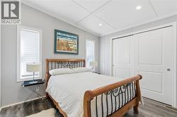 Bedroom with wood finished floors, lofted ceiling, a closet, and ornamental molding - 