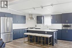 Kitchen featuring stainless steel appliances, a kitchen island, blue cabinetry, a kitchen breakfast bar, and vaulted ceiling - 