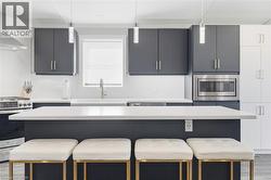 Kitchen with a kitchen bar, stainless steel appliances, modern cabinets, a center island, and pendant lighting - 