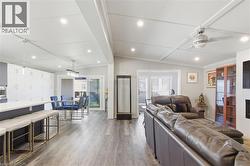Living room with dark wood finished floors, lofted ceiling, recessed lighting, ceiling fan, and healthy amount of natural light - 