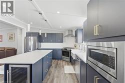 Kitchen with stainless steel appliances, vaulted ceiling, a kitchen island, beverage cooler, and blue cabinets - 