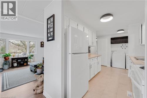 Kitchen with white cabinetry, light countertops, white appliances, and washing machine and clothes dryer - 157 Maple Crescent, Hamilton, ON - Indoor Photo Showing Kitchen