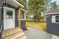 Wooden terrace with a yard, a storage unit, and a sunroom - 