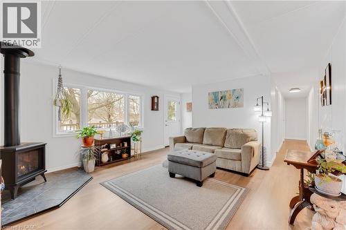 Living room with a wood stove, light wood-style flooring, and beamed ceiling - 157 Maple Crescent, Hamilton, ON - Indoor Photo Showing Living Room With Fireplace