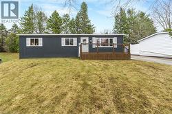 View of front facade featuring a wooden deck and a front lawn - 
