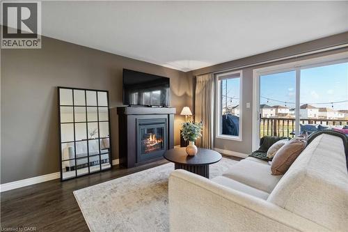 Living room with a glass covered fireplace and dark wood-type flooring - 27 Red Clover Crescent, Kitchener, ON - Indoor Photo Showing Living Room With Fireplace