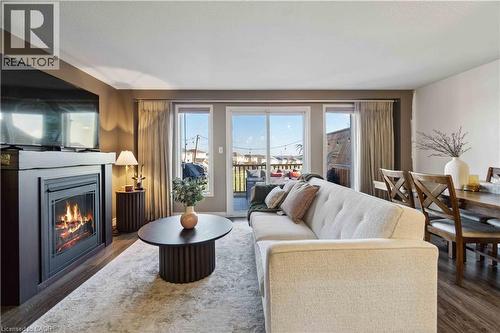 Living room with a glass covered fireplace and wood finished floors - 27 Red Clover Crescent, Kitchener, ON - Indoor Photo Showing Living Room With Fireplace