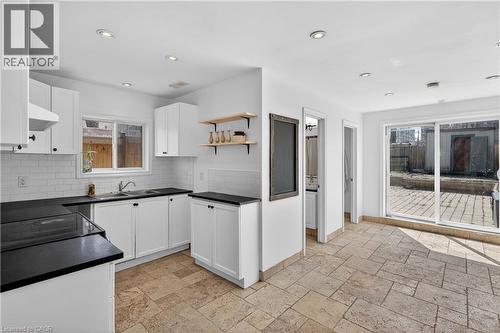 Kitchen featuring dark countertops, white cabinetry, stone tile flooring, open shelves, and exhaust hood - 216 Robert Street, Hamilton, ON - Indoor Photo Showing Kitchen With Double Sink With Upgraded Kitchen