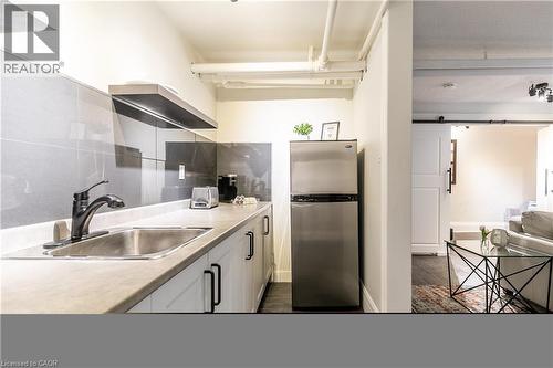 Kitchen featuring freestanding refrigerator, a barn door, white cabinetry, light countertops, and dark wood-style floors - 14 Duke Street, Hamilton, ON - Indoor Photo Showing Kitchen