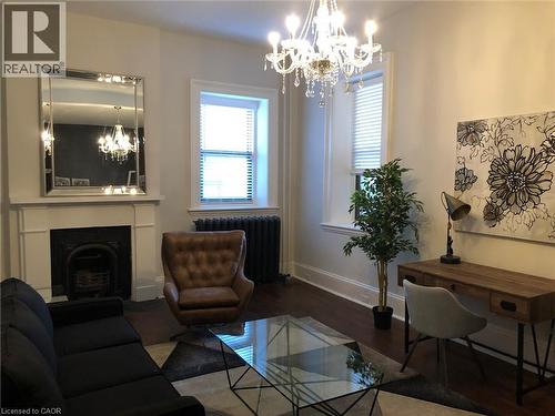 Living area featuring suspended lighting, radiator heating unit, wood finished floors, and plenty of natural light - 14 Duke Street, Hamilton, ON - Indoor With Fireplace
