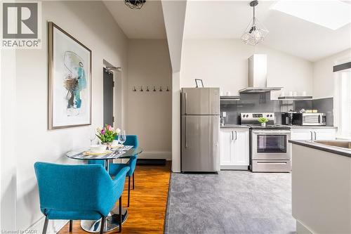 Kitchen with stainless steel appliances, white cabinets, ventilation hood, a skylight, and vaulted ceiling - 14 Duke Street, Hamilton, ON - Indoor Photo Showing Kitchen