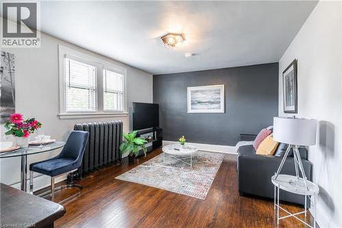 Living room featuring dark wood finished floors and an accent wall - 14 Duke Street, Hamilton, ON - Indoor Photo Showing Other Room