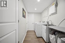 Laundry room with dark wood-type flooring, washing machine and clothes dryer, and recessed lighting - 