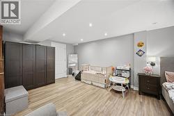 Bedroom with light wood-style flooring, a crib, and recessed lighting - 