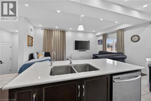 Kitchen featuring open floor plan, dark wood finish cabinetry, dishwasher, light tile patterned floors, and pendant lighting - 80 Severino Circle, Smithville, ON - Indoor Photo Showing Kitchen With Double Sink