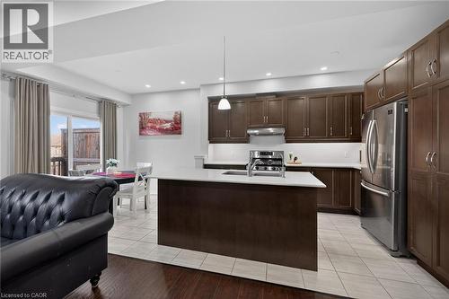 Kitchen featuring a kitchen island with sink, stainless steel appliances, dark wood finish cabinets, decorative light fixtures, and open floor plan - 80 Severino Circle, Smithville, ON - Indoor Photo Showing Kitchen With Double Sink