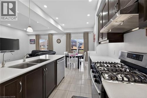 Kitchen with stainless steel appliances, dark wood finish cabinets, open floor plan, light stone countertops, and decorative light fixtures - 80 Severino Circle, Smithville, ON - Indoor Photo Showing Kitchen With Double Sink With Upgraded Kitchen