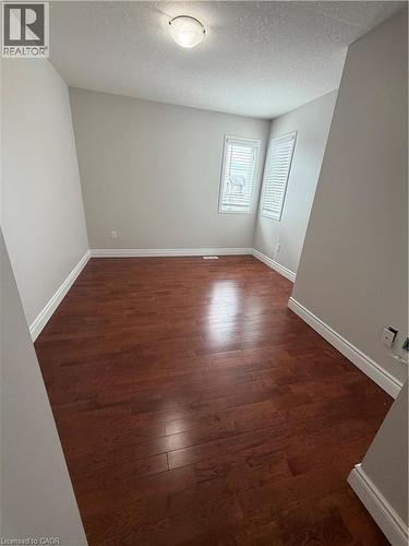 Spare room featuring dark wood-type flooring and a textured ceiling - 45 Brookfield Crescent, Kitchener, ON - Indoor Photo Showing Other Room