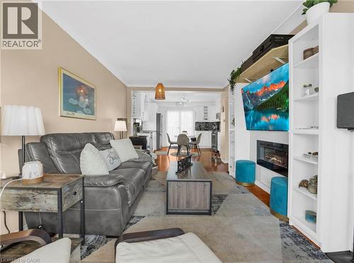 Living area with wood finished floors, ornamental molding, and a glass covered fireplace - 420 Waverly Street, Hamilton, ON - Indoor Photo Showing Living Room With Fireplace