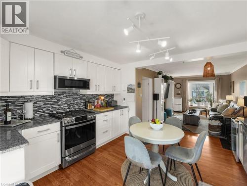 Kitchen with stainless steel appliances, white cabinets, open floor plan, dark wood finished floors, and dark stone countertops - 420 Waverly Street, Hamilton, ON - Indoor