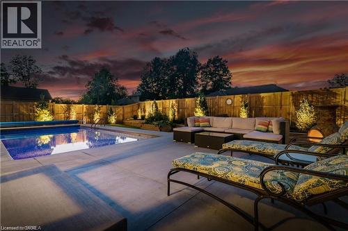 Pool at dusk with a fenced backyard, outdoor lounge area, and a patio area - 11 Sycamore Drive, Port Dover, ON - Outdoor With In Ground Pool