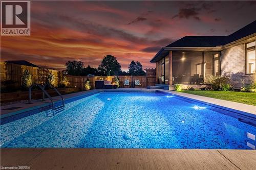 Pool at dusk featuring a fenced backyard, a sunroom, and a patio area - 11 Sycamore Drive, Port Dover, ON - Outdoor With In Ground Pool