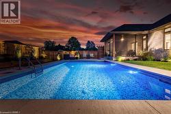 Pool at dusk featuring a fenced backyard, a sunroom, and a patio area - 